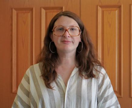 headshot of woman with white blouse, long brown hair, and glasses